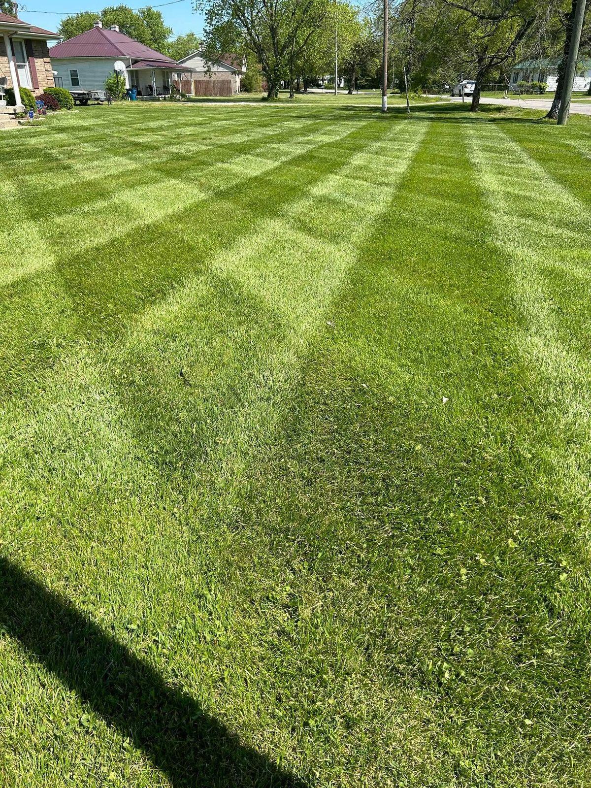 A front lawn cut into a light and dark checkerboard, every stripe holding its line